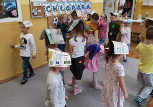 Dzieci tańczą z gazetą na głowie, tak aby nie spadła.